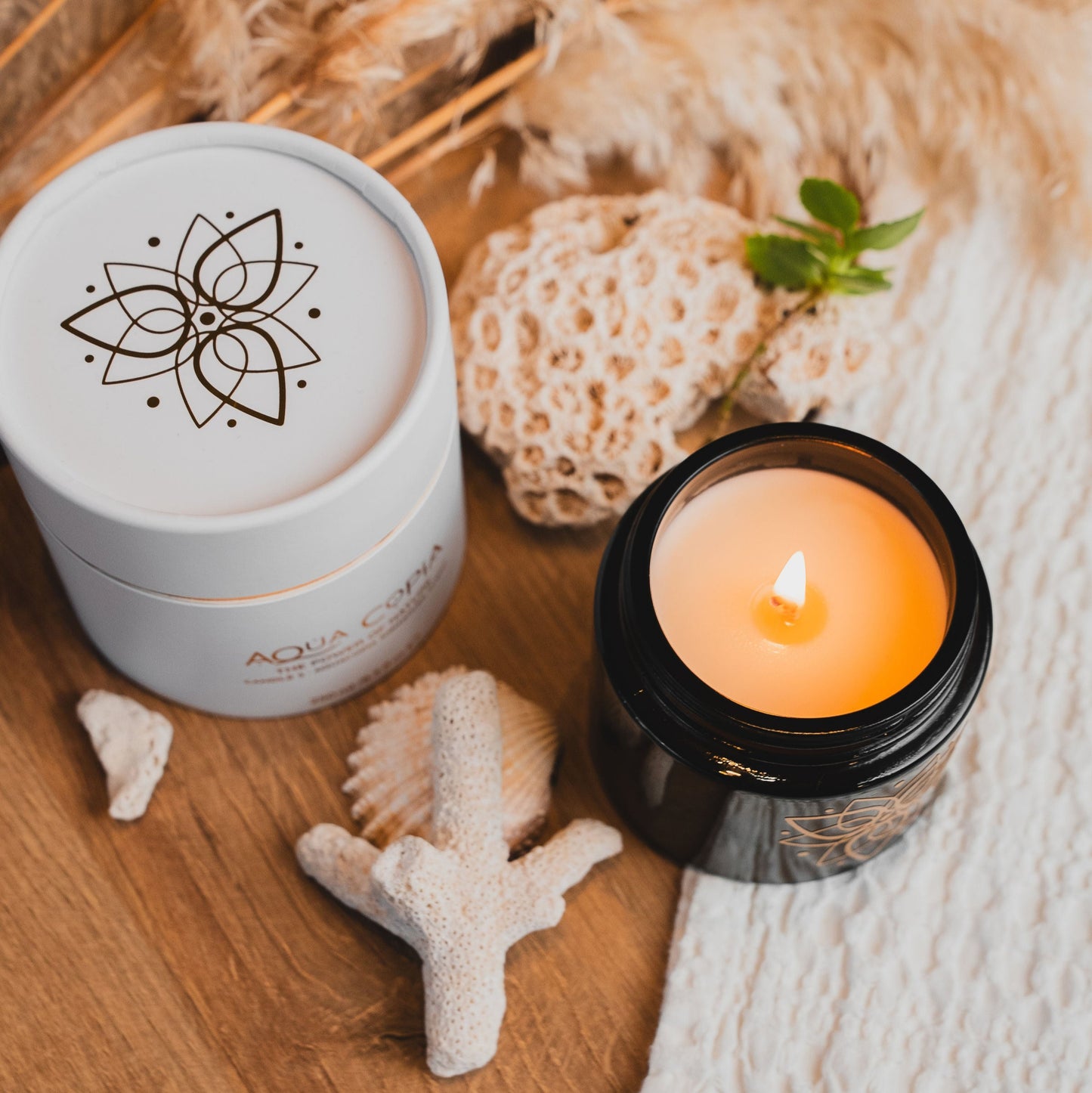 Candle and container with decorative elements on a wooden surface