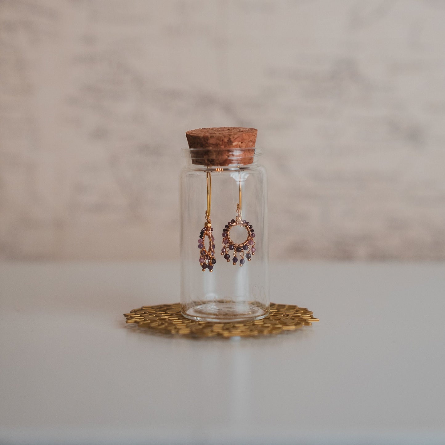 Glass jar with cork lid containing earrings on a marble surface