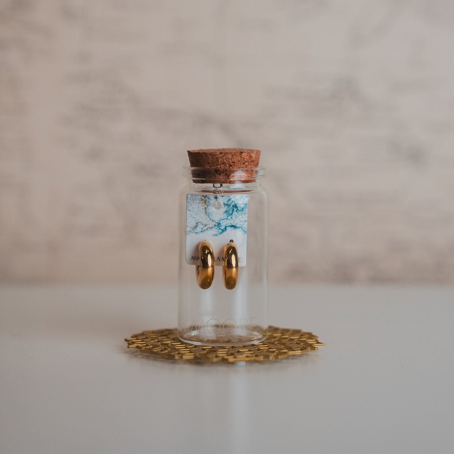 Small glass jar with cork lid on a decorative coaster against a marble background