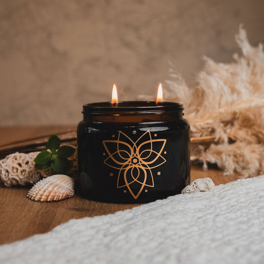 Black candle with floral design on a wooden surface with decorative elements.