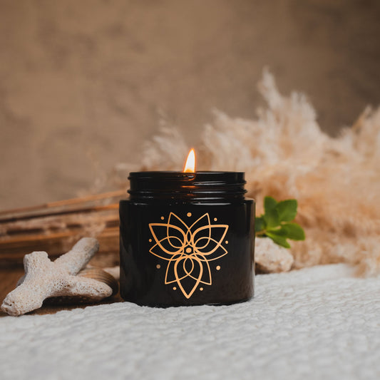 Black candle with a floral design on a textured surface with decorative elements.