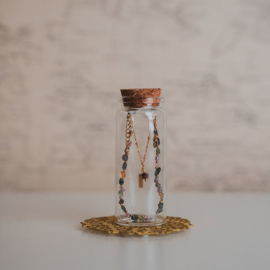 Glass bottle with necklaces on a textured surface and marble background