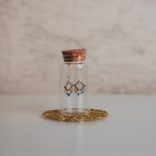 Earrings in a small glass jar on a white surface with a neutral background