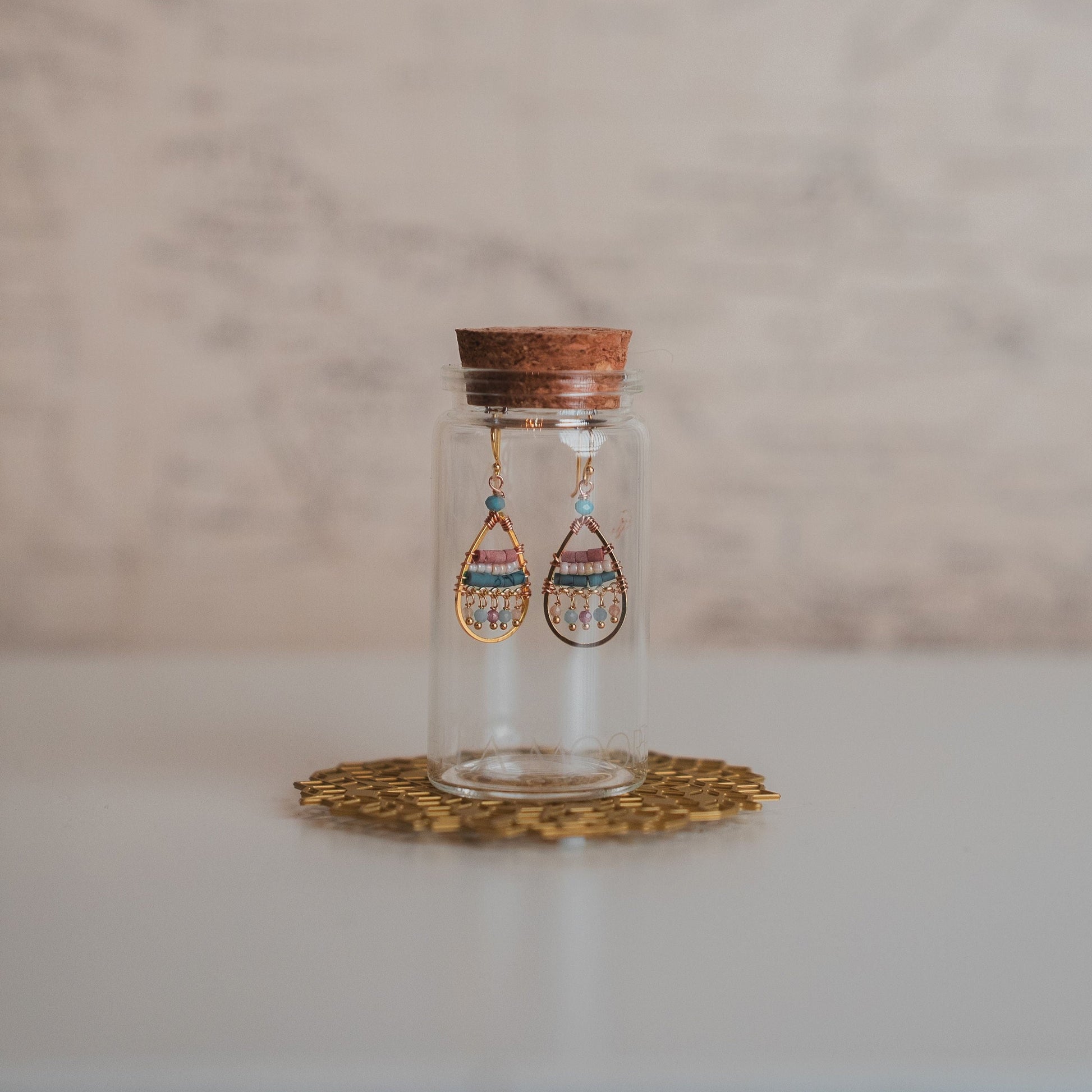 Glass jar with wooden lid containing earrings on a marble surface
