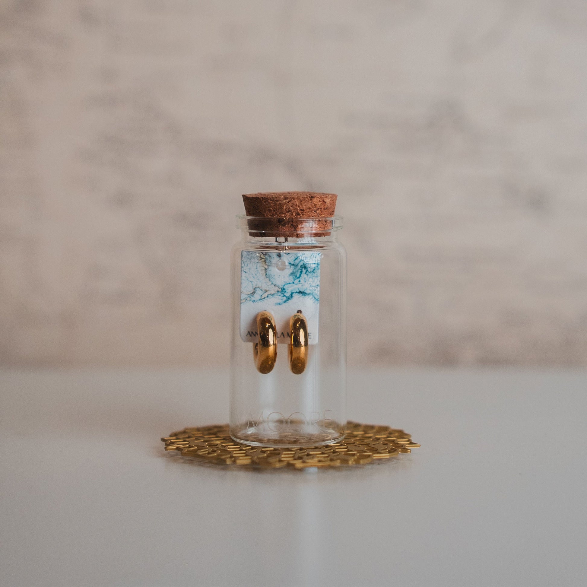 Small glass jar with cork lid on a decorative coaster against a marble background