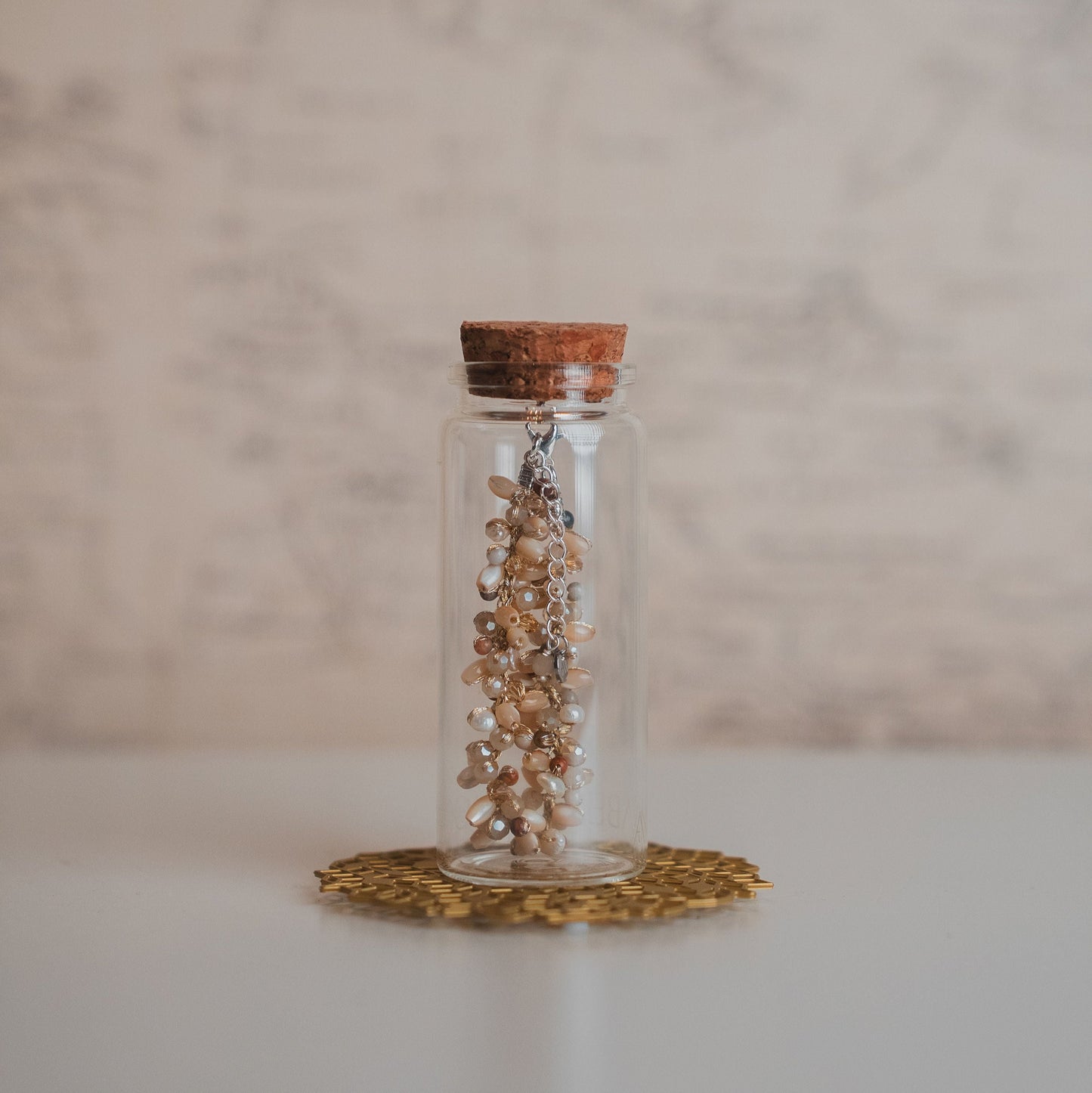 Glass jar with cork lid containing bracelet on a marble surface