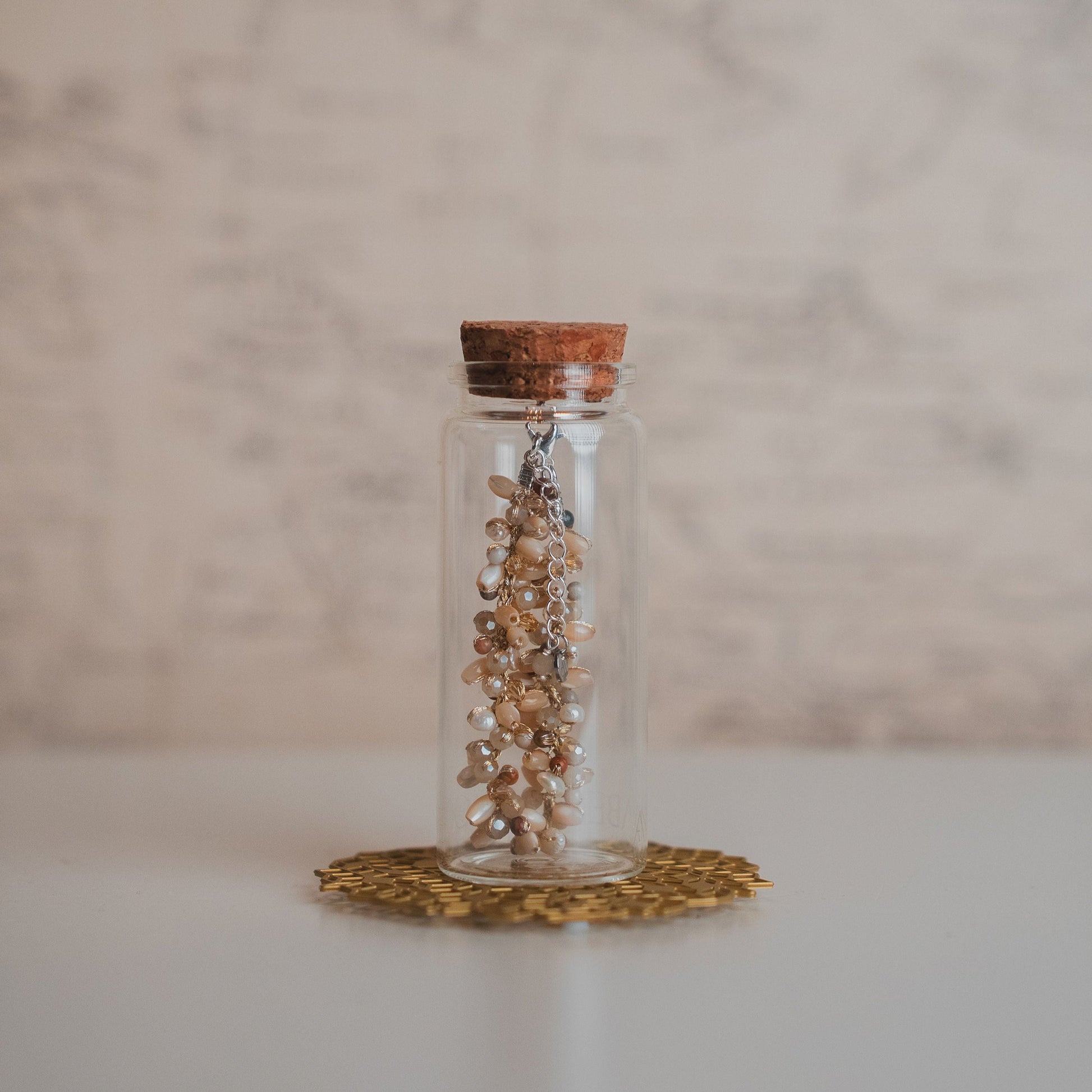 Glass jar with cork lid containing bracelet on a marble surface